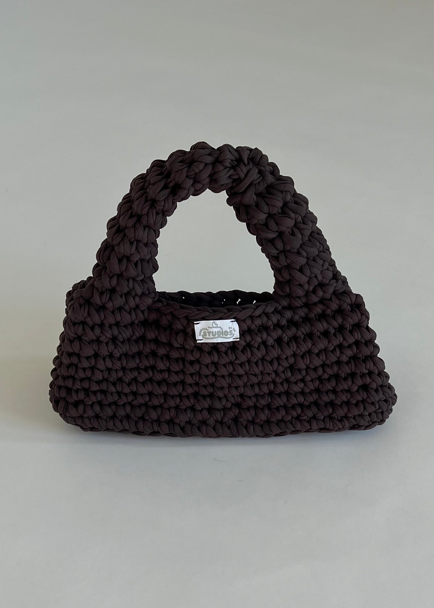 Handmade dark brown crochet handbag with a structured loaf shape. The Dark Roast Loaf is crafted from eco-friendly t-shirt yarn for everyday style with a bold twist.