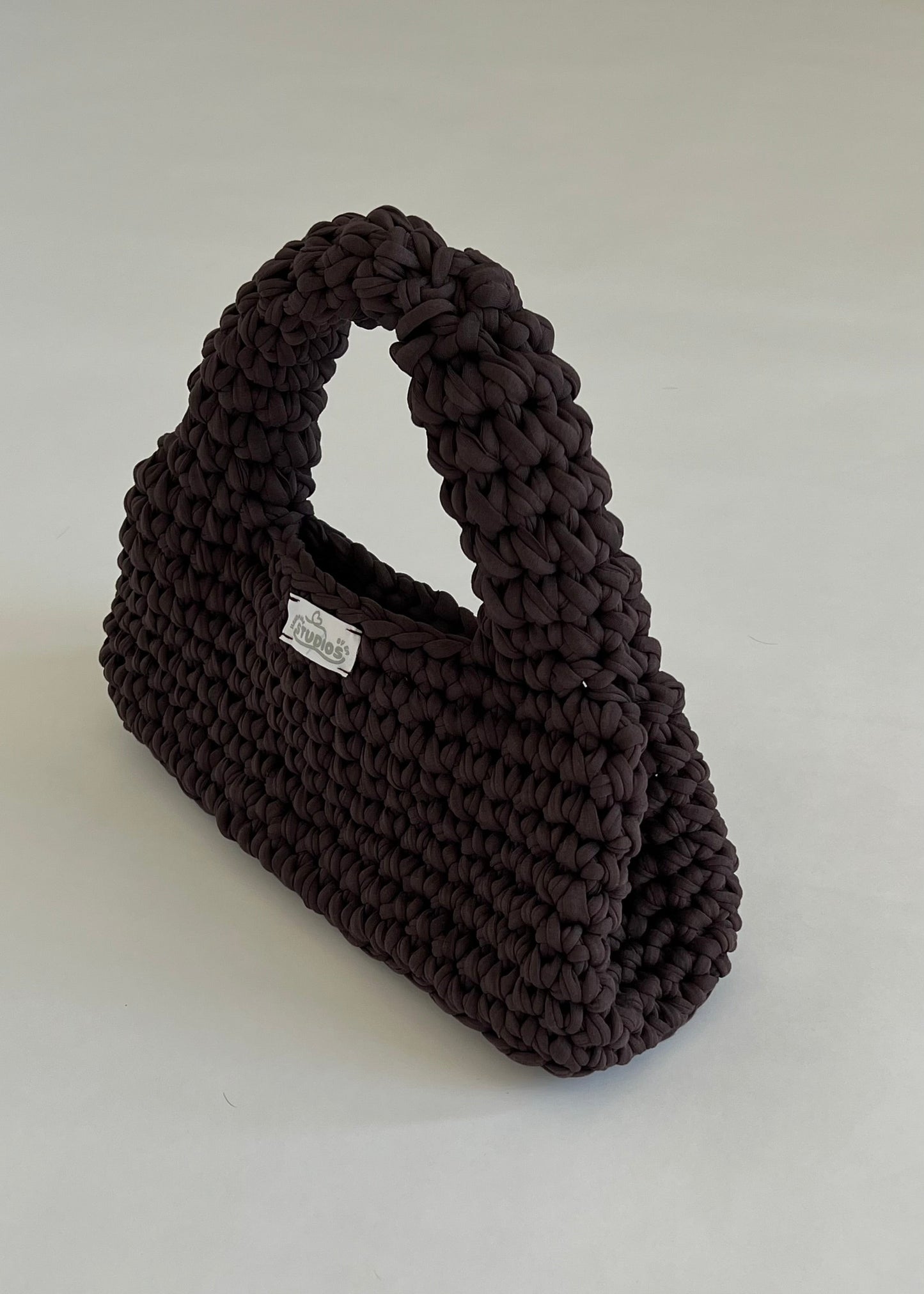 Handmade dark brown crochet handbag with a structured loaf shape. The Dark Roast Loaf is crafted from eco-friendly t-shirt yarn for everyday style with a bold twist.