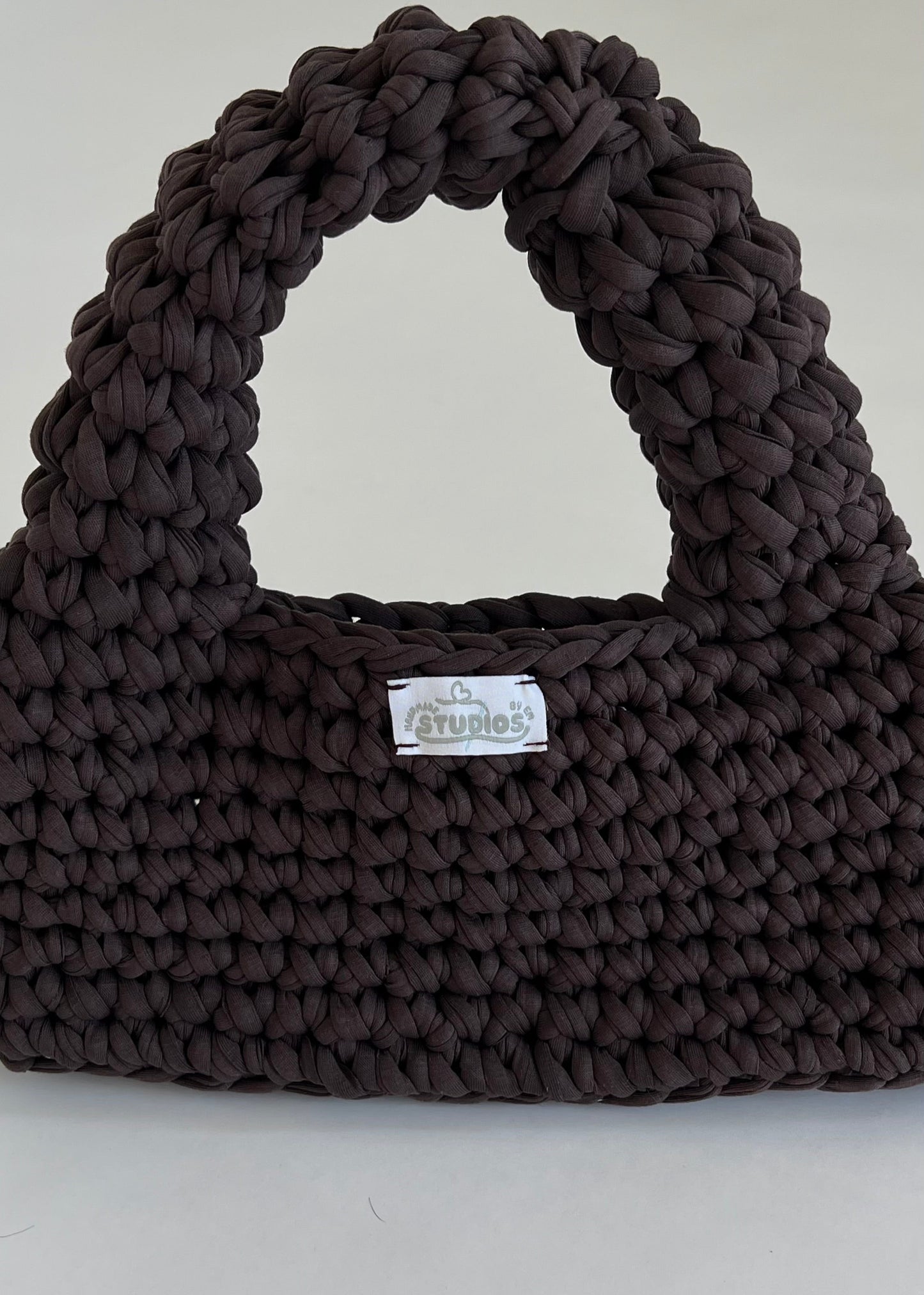 Handmade dark brown crochet handbag with a structured loaf shape. The Dark Roast Loaf is crafted from eco-friendly t-shirt yarn for everyday style with a bold twist.