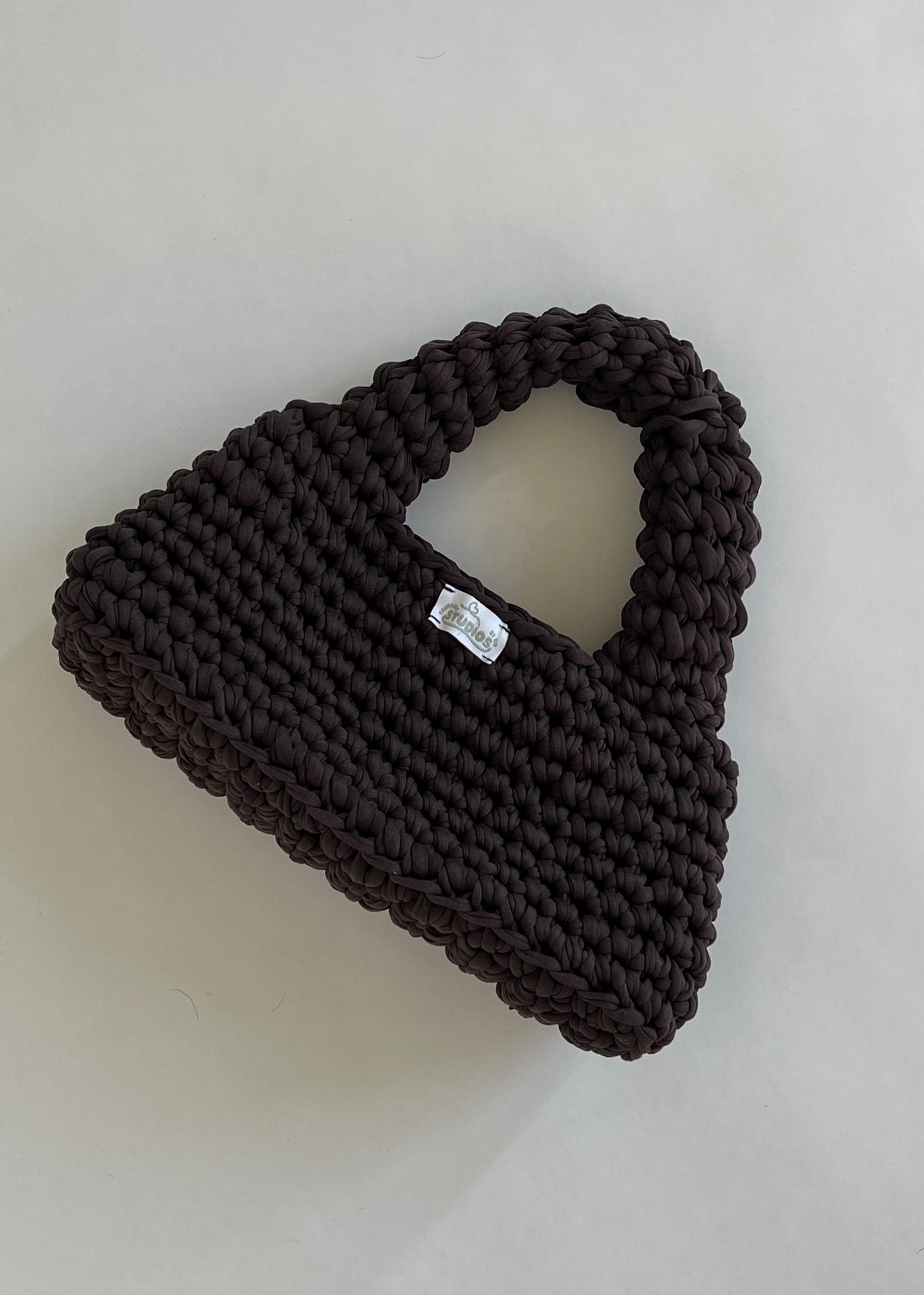 Handmade dark brown crochet handbag with a structured loaf shape. The Dark Roast Loaf is crafted from eco-friendly t-shirt yarn for everyday style with a bold twist.